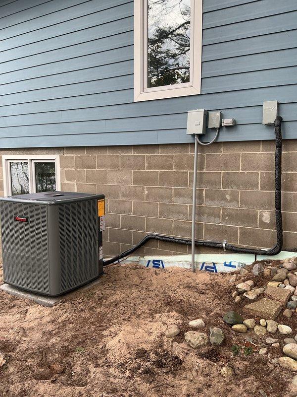 Completed full HVAC system replacement including installation of new furnace, air conditioning unit, and water heater. Interior furnace and water heater installed in basement utility area on protective mat with proper PVC venting, condensate drainage, and gas line connections. Exterior AC unit positioned on ground-level pad with refrigerant lines run through metal conduit along foundation wall, electrical disconnect boxes mounted, and all connections properly secured and tested for operation.