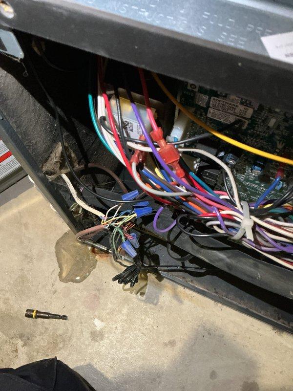 # No Heat Call - EnergiAir WT 04-2030 Unit

Responded to no heat call on 6-year-old EnergiAir WT 04-2030 system. Customer reported unit had operated previous day but now would not ignite, though flame was visible. Upon arrival, found evidence of significant moisture infiltration in mechanical room with water staining on concrete floor and condensation present on equipment panels and internal components.

Removed access panel to inspect burner assembly and control wiring. Observed multiple wire connections and control boards with moisture present. Noted water damage to concrete floor beneath unit and visible moisture droplets on metal panels and internal compartment surfaces.

Inspected gas valve, ignition system, and flame sensor assembly. Verified gas supply and pressure to unit. Examined all electrical connections including thermostat wiring, control board connections, and safety circuit components. Multiple colored wires (cyan, red, pink, purple, yellow, white, blue, black) were ins