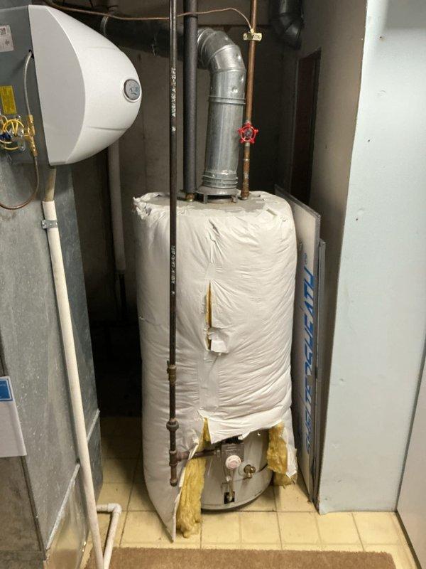 Responded to service call for water heater system with reported super low pressure and no visible water leaks after initial HVAC diagnostic attempt. Performed comprehensive inspection of water heater, expansion tank, and associated plumbing connections in mechanical room. Examined all supply lines, pressure relief valve, shut-off valves, and piping throughout the system including basement crawl space areas. Inspected expansion tank mounting and connections, verified proper installation of temperature and pressure relief valve with discharge piping. Assessed all copper supply lines, galvanized piping, and PVC drainage systems for potential pressure loss points. Documented equipment configuration including insulated water heater tank, wall-mounted expansion tank, and connection points to HVAC system. Investigated crawl space plumbing for hidden leaks or restrictions that could cause pressure issues. Photographed installation for service records showing mechanical room layout and undersid