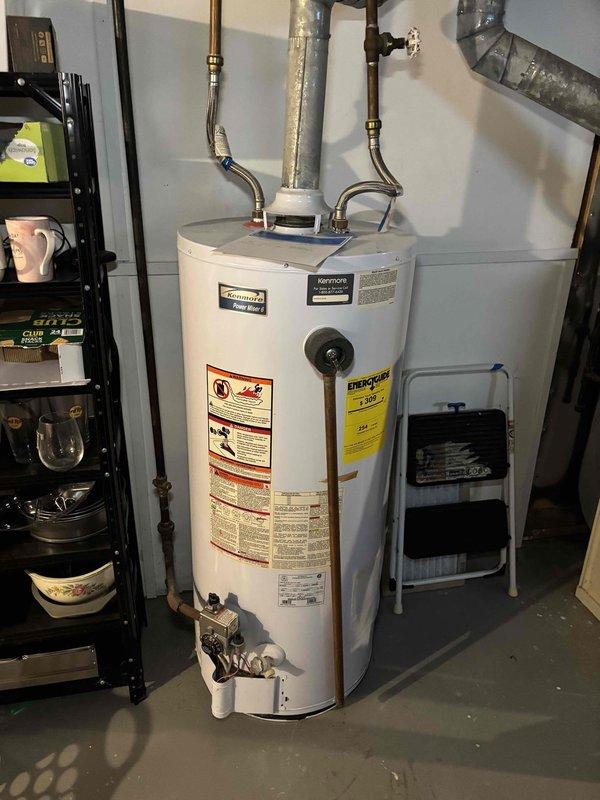Responded to service call for leaking tank water heater approximately 15 years old. Upon arrival, conducted visual inspection of unit and surrounding area. Documented existing conditions with photographs showing water heater installation, connected copper supply lines with brass fittings, and overall utility room setup. Assessed age and condition of water heater, noting unit had reached end of typical service life expectancy. Identified source of water leak and evaluated extent of damage to surrounding area. Reviewed findings with customer and discussed replacement options given age of equipment. Customer opted to proceed with scheduling through regular dispatch rather than emergency service. Membership benefits applied to service call.