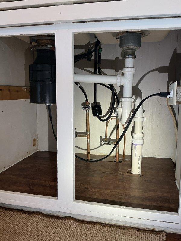 Completed PSI-Sink installation for double-basin stainless steel sink with chrome faucet, connecting all plumbing components including garbage disposal unit, supply lines, and drain assemblies under newly installed countertops. All connections tested and verified operational with no leaks detected.