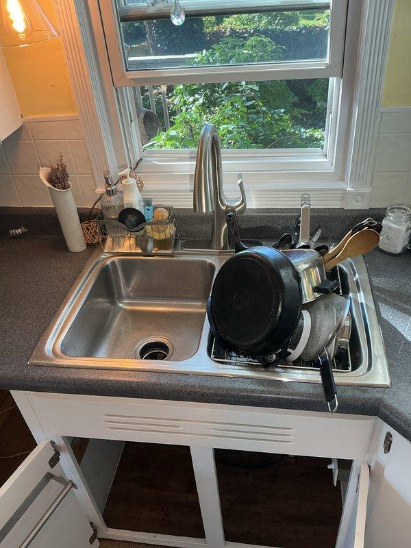 Completed PSI-Sink installation for double-basin stainless steel sink with chrome faucet, connecting all plumbing components including garbage disposal unit, supply lines, and drain assemblies under newly installed countertops. All connections tested and verified operational with no leaks detected.