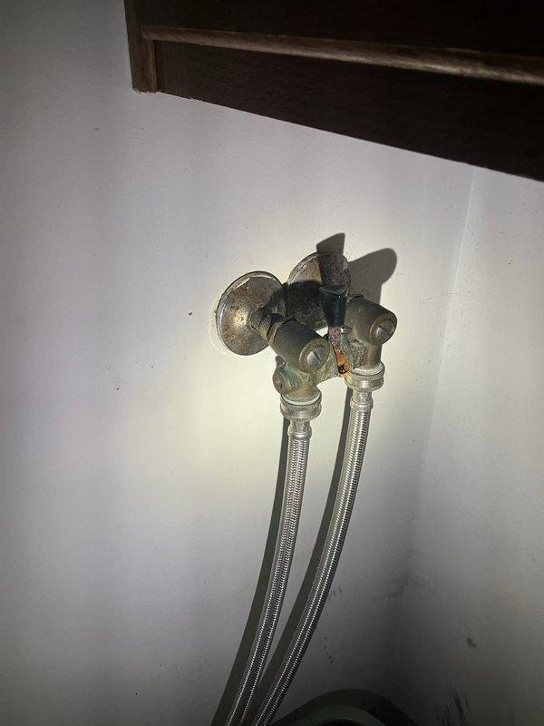 Responded to laundry room plumbing leak complaint and inspected water supply shut-off valves. Identified active leak at shut-off valve connection point and successfully replaced faulty valve assembly with new brass shut-off valves featuring gate-style handles. Verified proper installation of flexible braided stainless steel supply lines to wall-mounted connections, tested system for leaks, and confirmed full operational functionality with no further water seepage detected.