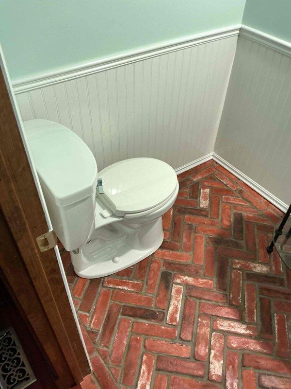 Completed installation of new toilet in powder room featuring herringbone brick flooring and beadboard wainscoting. Removed existing fixture, installed new two-piece porcelain toilet with chrome flush lever and water supply line, ensuring proper sealing and connection to existing plumbing. All work completed as quoted with customer satisfaction confirmed.