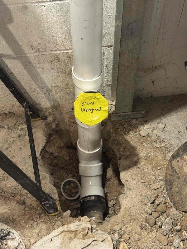 Installed new vertical drain stack through concrete foundation with proper underground drainage connection. Installed backwater valve assembly with PVC piping configuration in basement mechanical room, including multiple fittings and directional connections to prevent sewage backup. All components secured to foundation wall with appropriate support and access for future maintenance.