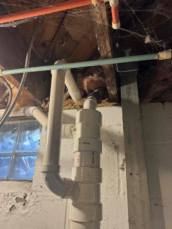 Installed new vertical drain stack through concrete foundation with proper underground drainage connection. Installed backwater valve assembly with PVC piping configuration in basement mechanical room, including multiple fittings and directional connections to prevent sewage backup. All components secured to foundation wall with appropriate support and access for future maintenance.