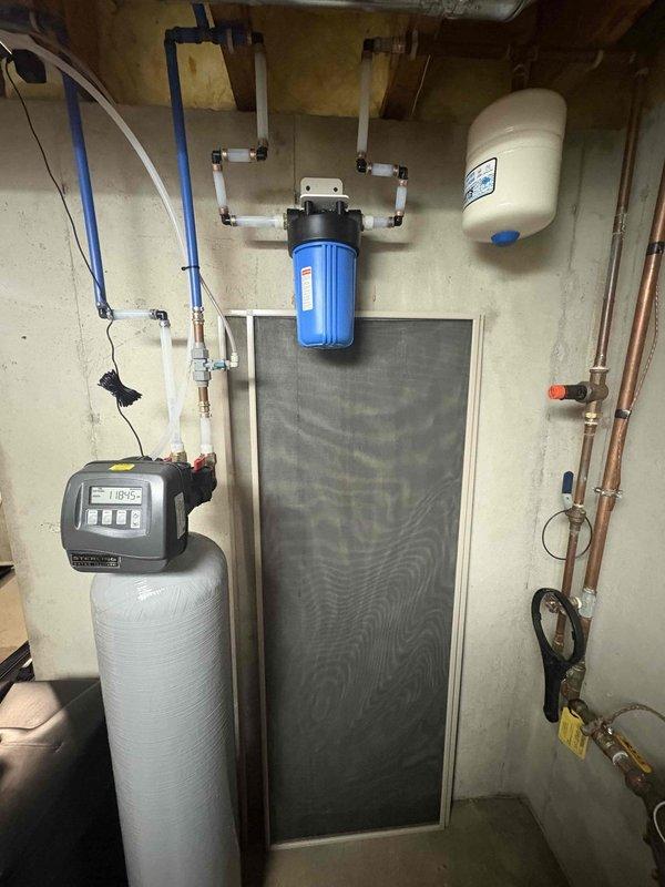 Installed a new whole-house water softener with a digital control valve head, connected to the existing supply plumbing with PEX and brass fittings, and mounted a sediment filter housing on the wall upstream of the system. Verified all connections for leaks, programmed the control valve, and confirmed proper operation of the softener, filter, and expansion tank with no visible damage to surrounding plumbing.