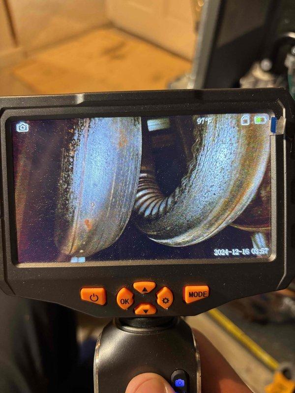 Performed a full tune-up on a 9-year-old furnace, including removal and inspection of the burner assemblies, which showed oxidation and soot buildup from heat exposure. Used a borescope to inspect the heat exchanger, noting minor surface rust and pitting along the weld seam, with no evidence of cracking or perforation. Cleaned the burners and verified safe, efficient operation.