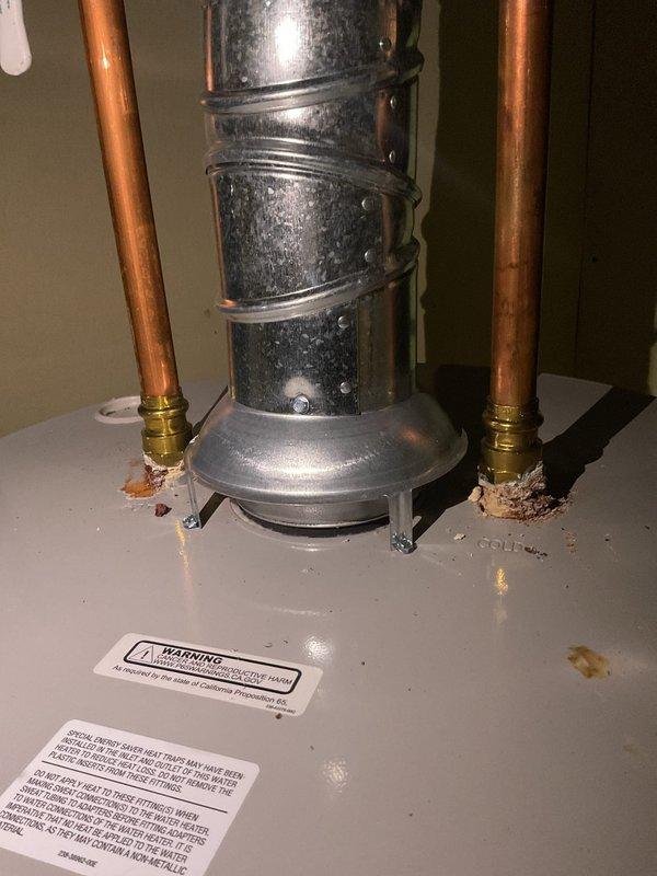Responded to a leak alarm on a Bradford White gas water heater with water collecting in the drain pan. Inspection of the tank top found corrosion and mineral deposits at both the hot and cold water connection fittings, identifying the leaking connections as the source. The unit was documented, and the corroded fittings were evaluated for repair to stop the leak and protect the pan and surrounding area.