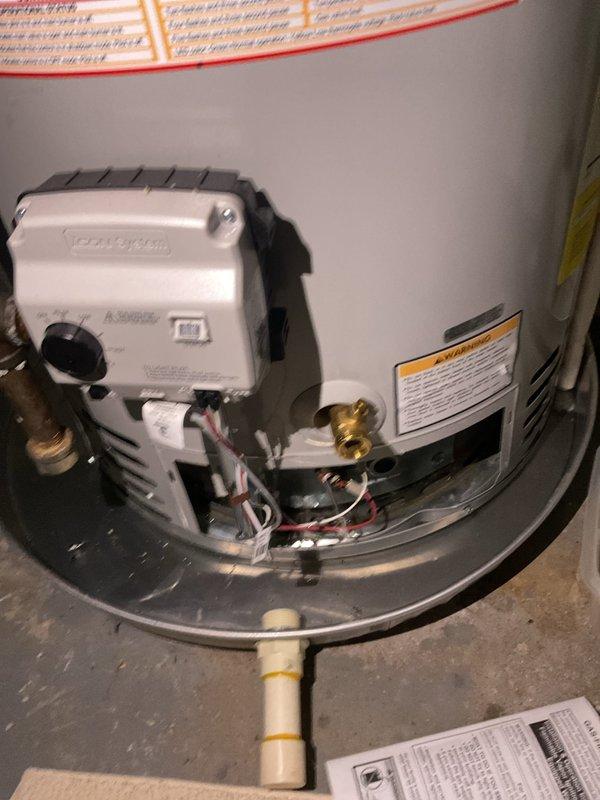 Responded to a leak alarm on a Bradford White gas water heater with water collecting in the drain pan. Inspection of the tank top found corrosion and mineral deposits at both the hot and cold water connection fittings, identifying the leaking connections as the source. The unit was documented, and the corroded fittings were evaluated for repair to stop the leak and protect the pan and surrounding area.