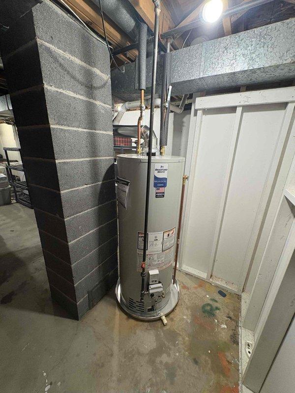 Installed a new Bradford White gas water heater in the basement utility area, set upright within a drain pan on the concrete floor. Connected the gas supply with a control valve, the water supply lines with a brass ball valve, and the flue to the existing vent, with insulation on the copper supply piping. Verified a secure, leak-free installation with no visible damage.