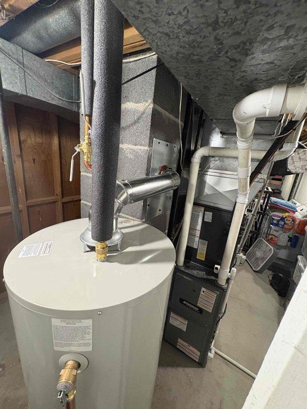Installed a new Bradford White gas water heater in the basement utility area, set upright within a drain pan on the concrete floor. Connected the gas supply with a control valve, the water supply lines with a brass ball valve, and the flue to the existing vent, with insulation on the copper supply piping. Verified a secure, leak-free installation with no visible damage.