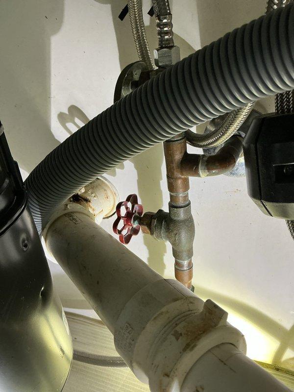 Inspected the kitchen sink drain and supply plumbing to locate the source of the reported leak. Found rust-colored staining and residue at the PVC slip-nut couplings and drain joints beneath the sink, indicating slow seepage at the threaded connections. The copper supply lines, shutoff valve, braided supply connectors, and disposal connections were also checked for moisture and showed no active leakage.