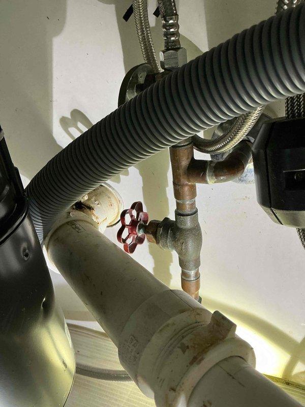 Inspected the kitchen sink drain and supply plumbing to locate the source of the reported leak. Found rust-colored staining and residue at the PVC slip-nut couplings and drain joints beneath the sink, indicating slow seepage at the threaded connections. The copper supply lines, shutoff valve, braided supply connectors, and disposal connections were also checked for moisture and showed no active leakage.