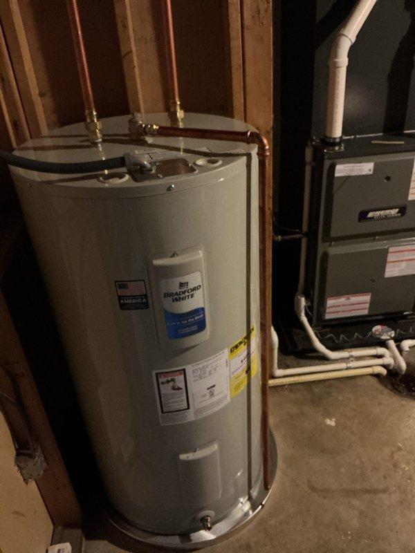 Installed a new 50-gallon tall electric Bradford White water heater in a drain pan, with copper supply connections, a drain valve, and a temperature and pressure relief discharge line routed to the floor drain. Verified connections are secure with no visible leaks, and the unit is properly positioned and ready for operation.
