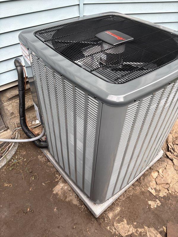 Installed a new add-on air conditioning system, setting the outdoor condenser on a level concrete pad and connecting it to the existing Payne gas furnace with a new evaporator coil cabinet. Ran the refrigerant line set and electrical connections, and tied the condensate drain into the existing PVC drain line routed to the condensate pump. Unit appears clean and undamaged with no visible leaks, frost, or defects.