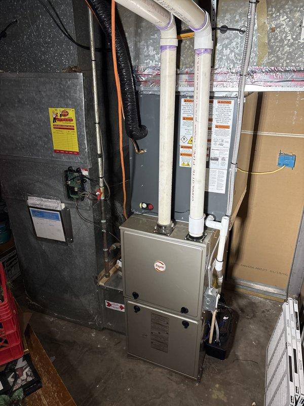 Installed a new add-on air conditioning system, setting the outdoor condenser on a level concrete pad and connecting it to the existing Payne gas furnace with a new evaporator coil cabinet. Ran the refrigerant line set and electrical connections, and tied the condensate drain into the existing PVC drain line routed to the condensate pump. Unit appears clean and undamaged with no visible leaks, frost, or defects.