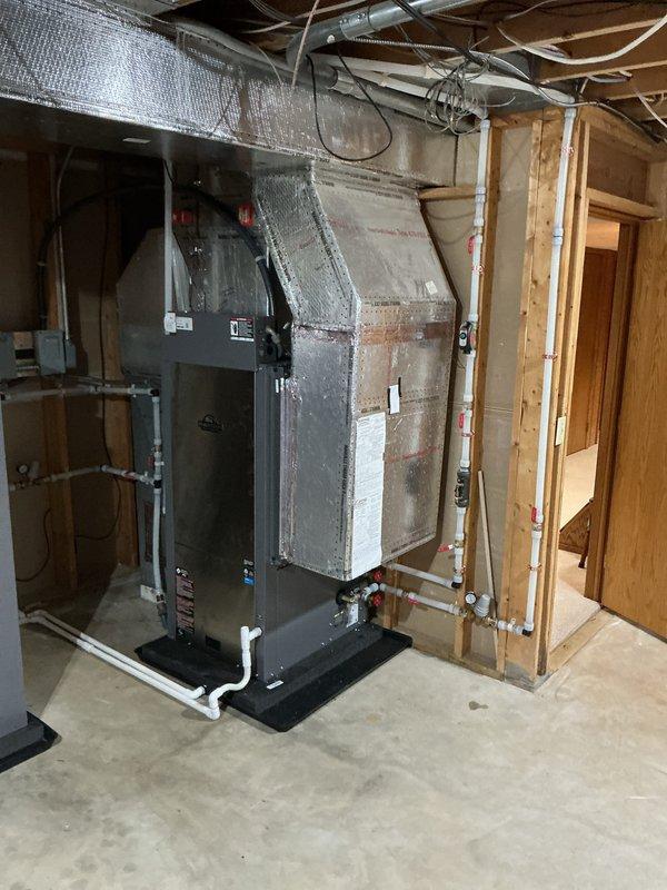 Installed a new geothermal heat pump system in the basement mechanical area, including a vertical air handler on a vibration-isolation pad with insulated supply plenum and ductwork connections. Completed the PVC loop piping with isolation valves, pressure gauges, and fittings, and mounted and wired the associated electrical disconnects and controls. System was left clean, properly secured, and free of visible leaks or damage.