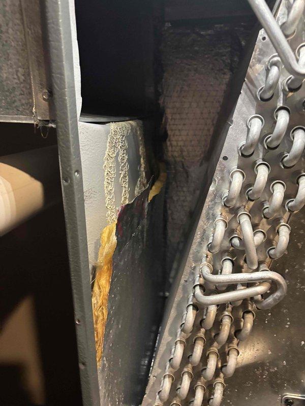 Responded to a no-cooling complaint on a system that had been running for hours without lowering indoor temperature. Measured a 49.2°F supply air reading at the air handler, indicating the refrigeration circuit was producing some cooling, and inspected the cabinet interior. Found the evaporator coil dirty and oxidized, a torn and delaminated duct board liner exposing fiberglass insulation, and heavy dust and debris buildup on the adjacent filter surface, all of which can restrict airflow and degrade heat transfer and system capacity. Documented these conditions with photos and identified them as contributing factors to the reduced cooling performance.