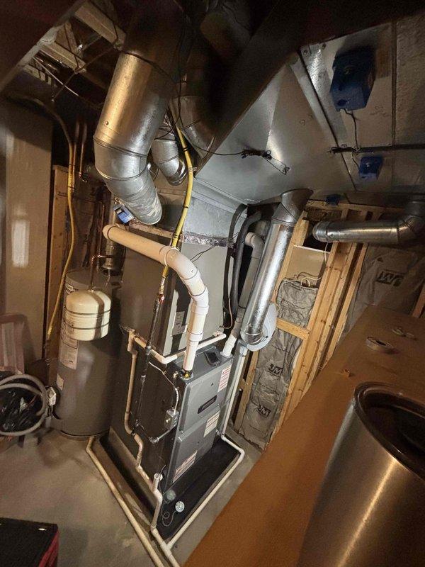 Installed a new upright high-efficiency gas furnace with supply plenum and galvanized ductwork connections, including PVC combustion venting, condensate drain piping, and a flexible gas line connection. Mounted and connected an AprilAire humidifier to the plenum with a dedicated water supply line, and posted the service log sheet on the ductwork for future maintenance records. Completed the installation with a clean, code-compliant mechanical layout and no visible damage or leaks.