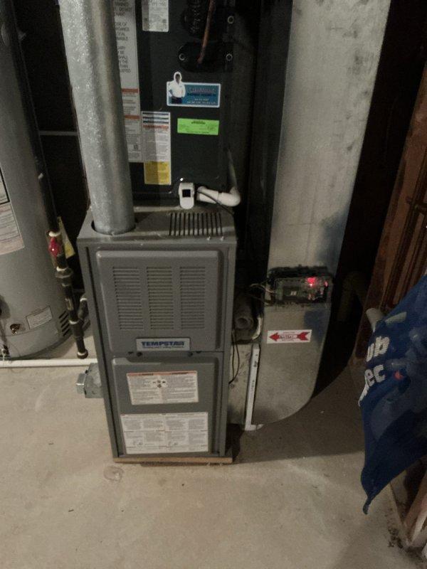 Performed an on-site evaluation of a non-operational 22-year-old Tempstar upright gas furnace with an attached evaporator coil cabinet and an air-exchange unit, and documented the equipment, flue, condensate drain, and gas piping with photos. The furnace was found intact with no visible rust, frost, or damage, though a small amount of airflow was reported coming from the unit while idle, and the system's age warrants replacement consideration. A replacement estimate was presented, and the homeowner is weighing their options.