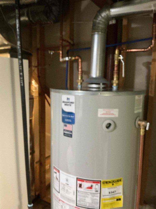 Installed a new 75-gallon natural gas Bradford White tank-style water heater, connecting the copper supply lines with brass shutoff valves and routing the galvanized flue to the existing overhead vent. Connected the temperature and pressure relief valve discharge piping, and verified the unit is clean, properly secured, and free of visible leaks or damage.