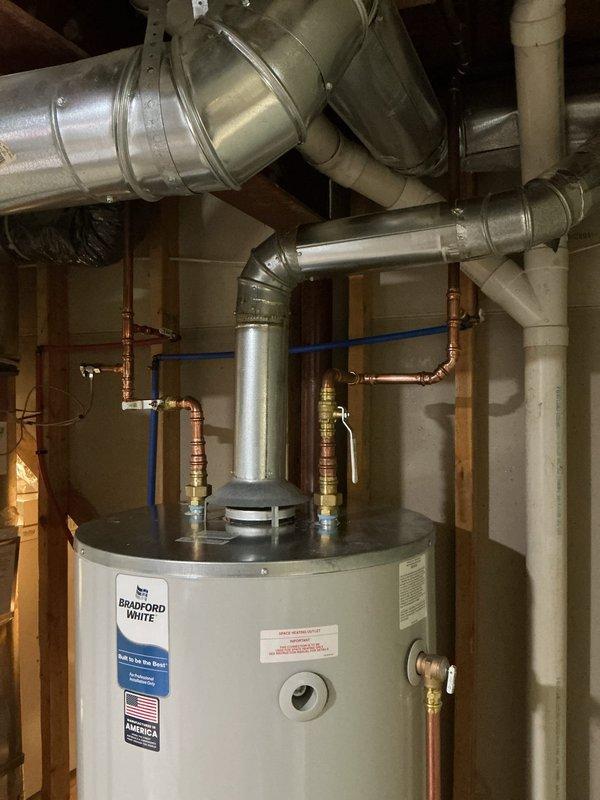 Installed a new 75-gallon natural gas Bradford White tank-style water heater, connecting the copper supply lines with brass shutoff valves and routing the galvanized flue to the existing overhead vent. Connected the temperature and pressure relief valve discharge piping, and verified the unit is clean, properly secured, and free of visible leaks or damage.