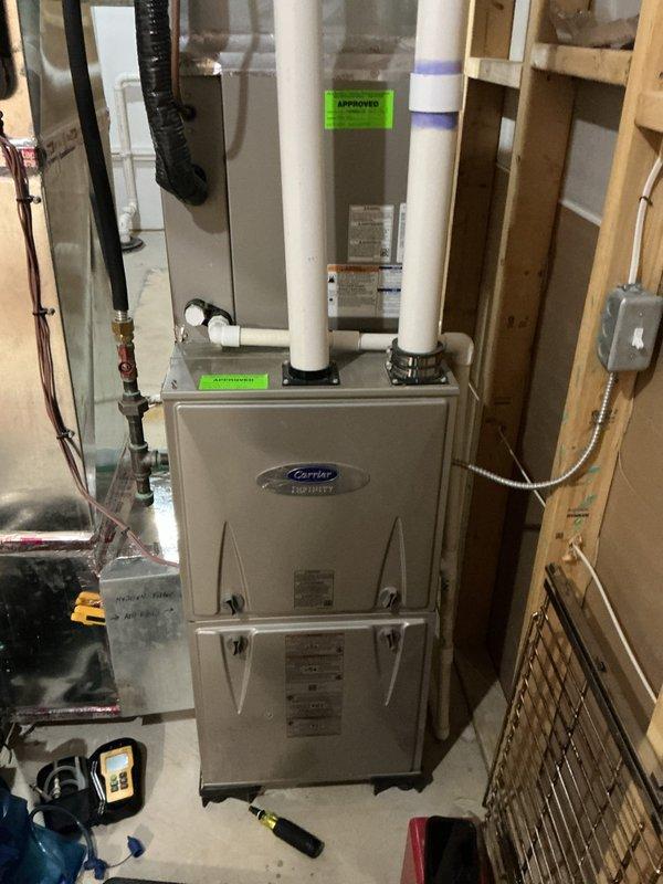 Performed a complete tune-up on a Carrier Infinity gas furnace, including inspection of the burner assembly, venting, gas connections, and electrical components, with the system operating normally and showing no signs of rust, frost, or damage. Inspected the Aprilaire 500M humidifier and noted heavy condensation on the adjacent supply duct. Equipment is in good working condition, with the furnace covered under a 6-year service plan.
