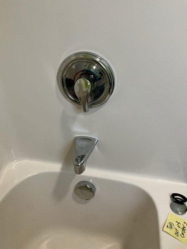 Inspected the tub and shower assembly to locate the source of the leak affecting the ceiling below, examining the valve trim, tub spout, and drain components. The tub drain stopper and gasket were found detached from the drain opening, so the drain assembly was exposed and a likely contributor to the water intrusion. No visible cracks, corrosion, or buildup were found on the surrounding fixtures or surfaces, and the drain components were documented for follow-up repair.