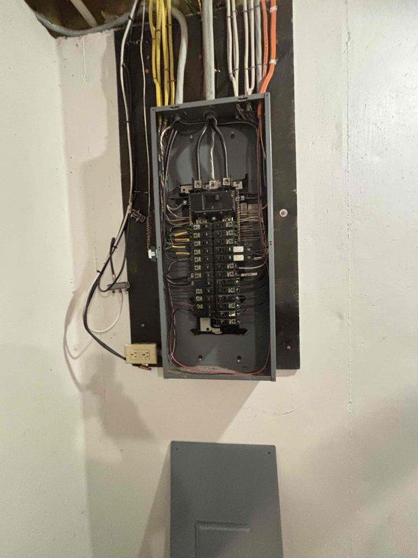 Inspected the main electrical service panel and existing branch circuit wiring to evaluate capacity and feasibility for the requested living room lighting and ceiling fan installation. Observed dense, congested conductor routing within the enclosure and assessed available breaker space and circuit loading to determine the appropriate scope of work. Documented panel conditions with photographs to support quote preparation for the new lighting and fan circuit.