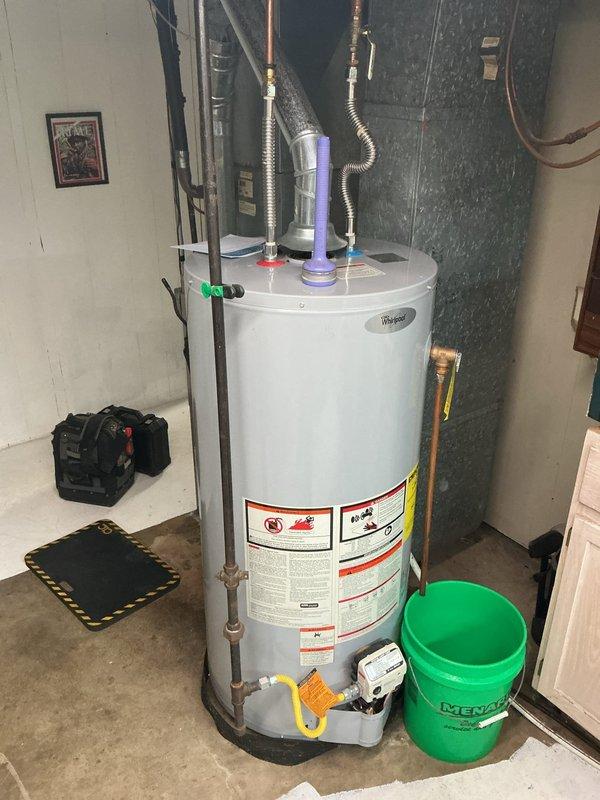 Performed a comprehensive tune-up on a 21-year-old gas furnace, including inspection of the cabinet, flue venting, and ductwork connections, and verification of safe operation. Cleaned accumulated dirt and debris from the equipment area, checked gas piping and controls, and confirmed proper flue connection to the chimney/duct system with no visible corrosion or damage. Also inspected the adjacent water heater, noting the T&P relief discharge, gas control valve, and supply connectors in serviceable condition with no leaks or rust observed.