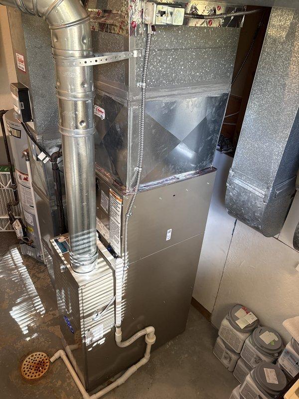 Installed a new upright gas furnace with matching AC components, connecting the supply plenum and ductwork, galvanized flue vent, and gas and electrical supply through flexible conduit to the junction box. Routed and secured the PVC condensate drain piping to the floor drain, and verified all connections, equipment labeling, and system operation, leaving the unit clean with no visible damage.