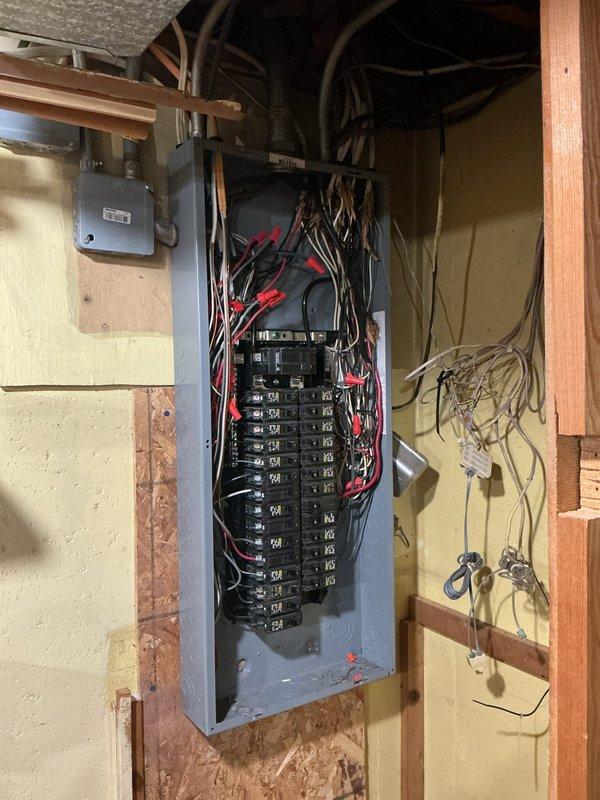 Performed an Electrical Club Inspection of the main service panel with the cover removed, evaluating the main breaker, branch circuit breakers, conductor routing, and terminations. Identified disorganized, fanned-out conductors with possible frayed insulation at the upper panel area, debris within the enclosure, and loose, unterminated low-voltage wiring adjacent to the panel. Recommend a licensed electrician perform a follow-up evaluation to clean and organize the panel wiring, verify and correct terminations, and properly terminate or secure the low-voltage conductors.
