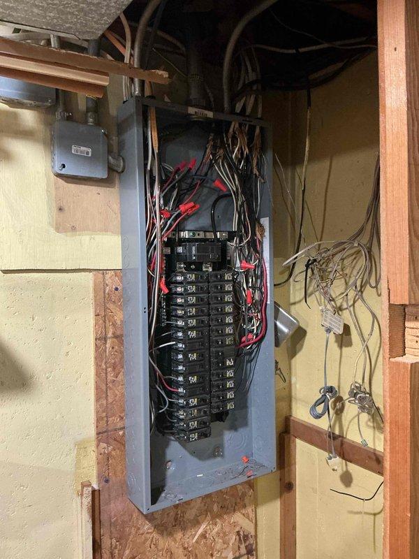 Performed an Electrical Club Inspection of the main service panel with the cover removed, evaluating the main breaker, branch circuit breakers, conductor routing, and terminations. Identified disorganized, fanned-out conductors with possible frayed insulation at the upper panel area, debris within the enclosure, and loose, unterminated low-voltage wiring adjacent to the panel. Recommend a licensed electrician perform a follow-up evaluation to clean and organize the panel wiring, verify and correct terminations, and properly terminate or secure the low-voltage conductors.