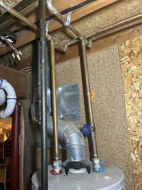 Performed an on-site estimate for a 19-year-old water heater reported to be leaking from the top, inspecting the tank top, hot and cold water supply connections, shut-off valve, and flue venting assembly. Observed water-spotting and mild residue on the flue elbow sections, and the unit's age indicates it has exceeded its typical service life, so replacement is recommended and the estimate was documented with photos.