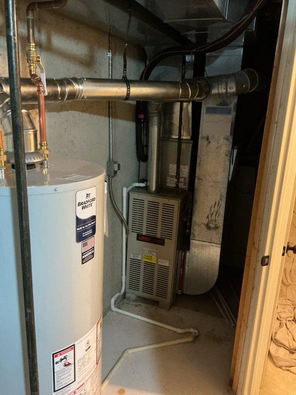 Installed a new Bradford White gas-fired water heater on a metal drain pan, connecting copper supply lines with shutoff valves and tying the draft hood into the existing metal flue vent. Connected the gas control valve and routed the drain line to the existing condensate drain. Verified all connections were secure with no leaks, rust, or damage visible, and left the work area clean and operational.
