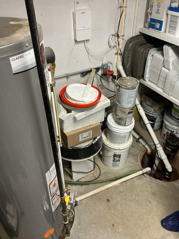 Responded to a reported malfunction on a 9-year-old Rheem Classic Series gas tank water heater and inspected the unit, its gas supply piping and shutoff valve, and the galvanized flue/vent connection at the ceiling penetration. Observed soot staining and debris around the flue opening with a gap between the vent pipe and the ceiling cutout, and noted the surrounding area is cluttered with stored materials near the appliance, which may affect combustion air and clearance; repair options were quoted on site.