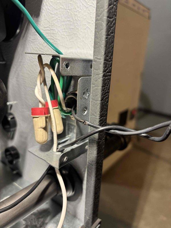 Responded to a no-heat call on a newly installed furnace and AC system with the thermostat displaying a "call for service" message. Inspected the cabinet wiring and found loosely arranged line-voltage conductors at the junction box bracket, including a conductor with nicked insulation and evidence of scorching near the bracket flange. Repaired and secured the damaged wiring and wire-nut connections, restored proper power to the unit, and verified normal operation and thermostat communication.