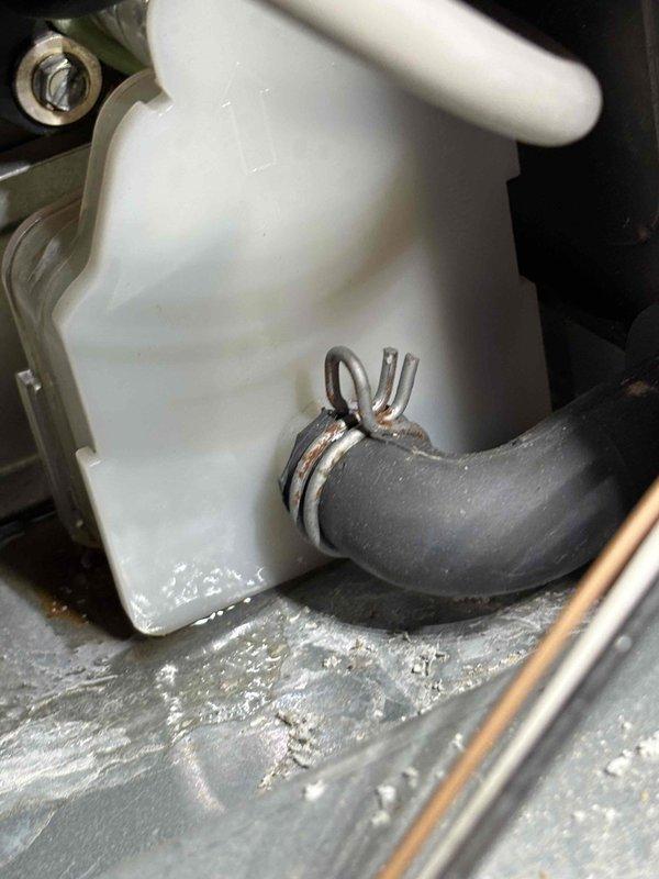 Inspected the furnace for the reported water leak and traced it to the condensate drain system, where the rubber drain hose connection at the collection reservoir was seeping due to a corroded, deteriorated spring clamp and mineral buildup around the fitting. Cleared the debris and scale from the affected area and restored a secure, watertight hose connection, confirming the leak was resolved and condensate drains properly.