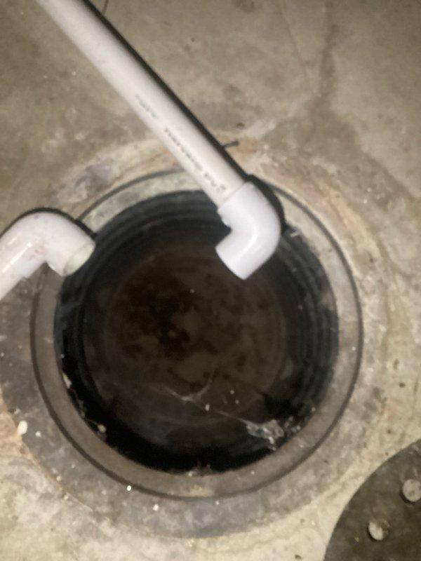 Inspected the reported slow floor drain and opened the wall cavity behind the furnace to trace the drain line, then checked the nearby sump pit, which contained murky sediment and debris around the discharge piping. The affected drain and sump piping were evaluated and the area was left accessible for further service or repair if required.