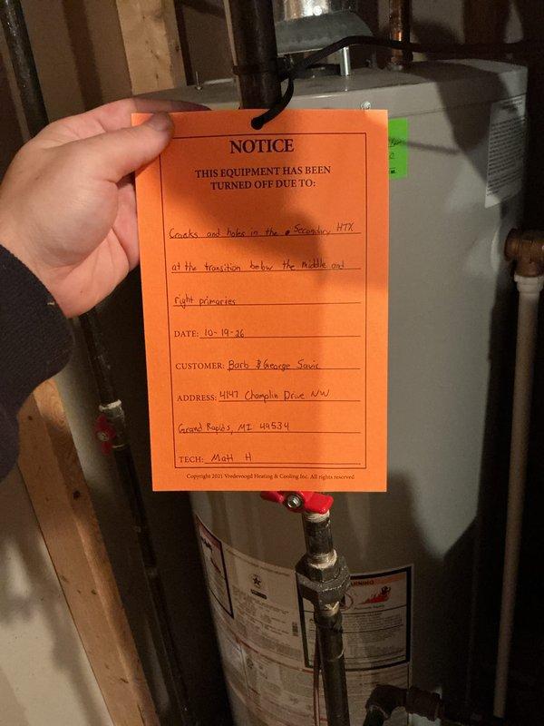 Performed annual heating tune-up on a 14-year-old high-efficiency gas furnace and associated humidifier. During inspection, cracks and holes were identified in the heat exchanger, and a red tag "NOTICE" was affixed to the unit documenting the condition and the unsafe-operation hazard. Furnace and humidifier maintenance were completed per annual service scope, with no frost, rust, or visible external damage noted on the surrounding equipment.