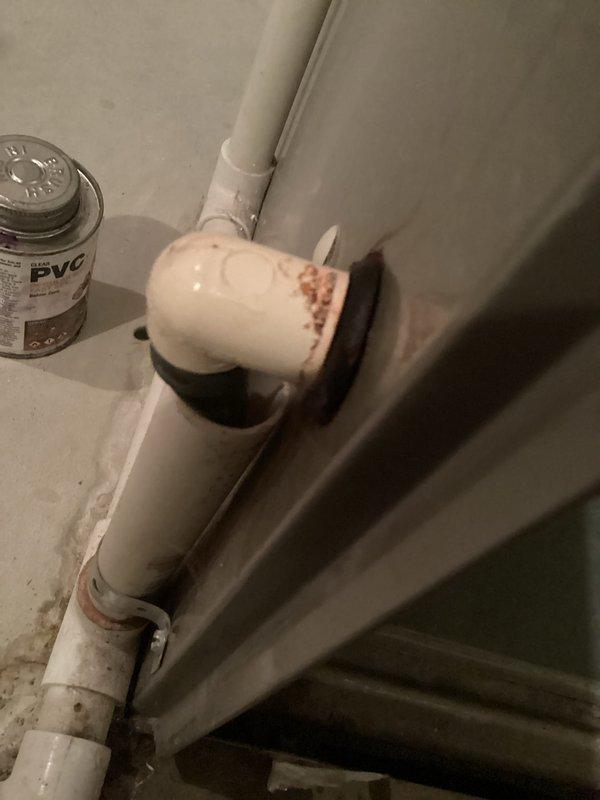 Responded to a water leak at the left side of a 16-year-old Carrier furnace and traced the source to the PVC condensate drain connection at the cabinet penetration, where the elbow fitting and grommet showed rust staining and moisture residue. Inspected the condensate drain line and fittings, then repaired the leaking connection and secured the piping to restore proper drainage and eliminate the leak.