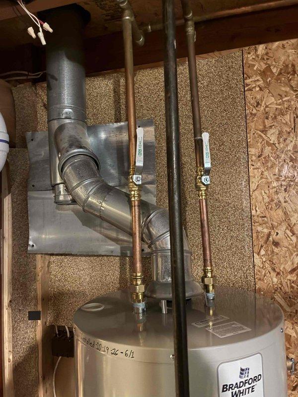 Installed a new 40-gallon tall natural gas Bradford White water heater, connecting the hot and cold copper water lines with brass fittings and quarter-turn ball valves, and routing the metal flue to the existing vent with a wall heat shield for clearance. The unit is secured in the utility space and ready for operation.
