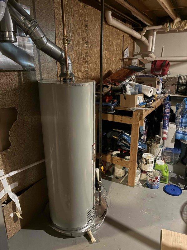 Installed a new 40-gallon tall natural gas Bradford White water heater, connecting the hot and cold copper water lines with brass fittings and quarter-turn ball valves, and routing the metal flue to the existing vent with a wall heat shield for clearance. The unit is secured in the utility space and ready for operation.