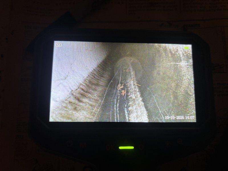 Responded to a no-heat call on a 10-year-old furnace with the blower running but no heat output. Used a borescope to inspect the venting and found the exhaust/intake piping partially obstructed by leaf and soil debris, with additional sediment buildup and a crack noted in the interior of the flue passage. The blockage restricts combustion airflow and is the likely cause of the no-heat condition; the debris obstruction was documented with photos and the system should be cleared and the cracked venting evaluated for repair before returning to service.