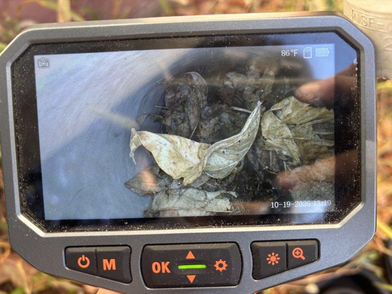 Responded to a no-heat call on a 10-year-old furnace with the blower running but no heat output. Used a borescope to inspect the venting and found the exhaust/intake piping partially obstructed by leaf and soil debris, with additional sediment buildup and a crack noted in the interior of the flue passage. The blockage restricts combustion airflow and is the likely cause of the no-heat condition; the debris obstruction was documented with photos and the system should be cleared and the cracked venting evaluated for repair before returning to service.