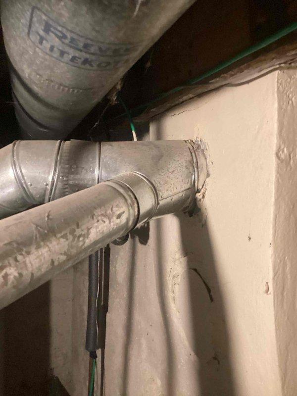 Inspected the existing natural gas tank water heater following a reported overflow and assessed the installation for replacement, including the draft hood and galvanized flue vent, copper water connections with ball valve, and surrounding electrical and ductwork. Documented unit condition, including moisture and rust-colored residue at the flue and pipe connections, and prepared an estimate for supply and installation of a new natural gas tank water heater.