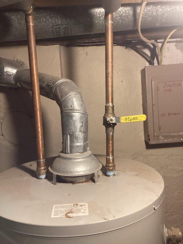 Inspected the existing natural gas tank water heater following a reported overflow and assessed the installation for replacement, including the draft hood and galvanized flue vent, copper water connections with ball valve, and surrounding electrical and ductwork. Documented unit condition, including moisture and rust-colored residue at the flue and pipe connections, and prepared an estimate for supply and installation of a new natural gas tank water heater.