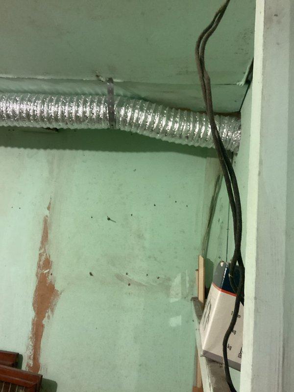 Installed a flexible aluminum dryer vent duct running along the wall below the ceiling and routed it through the exterior wall penetration, securing it with metal band clamps for proper support and alignment. Connected the duct to the dryer to provide exhaust ventilation, and confirmed a tight, unobstructed run with secure fittings.