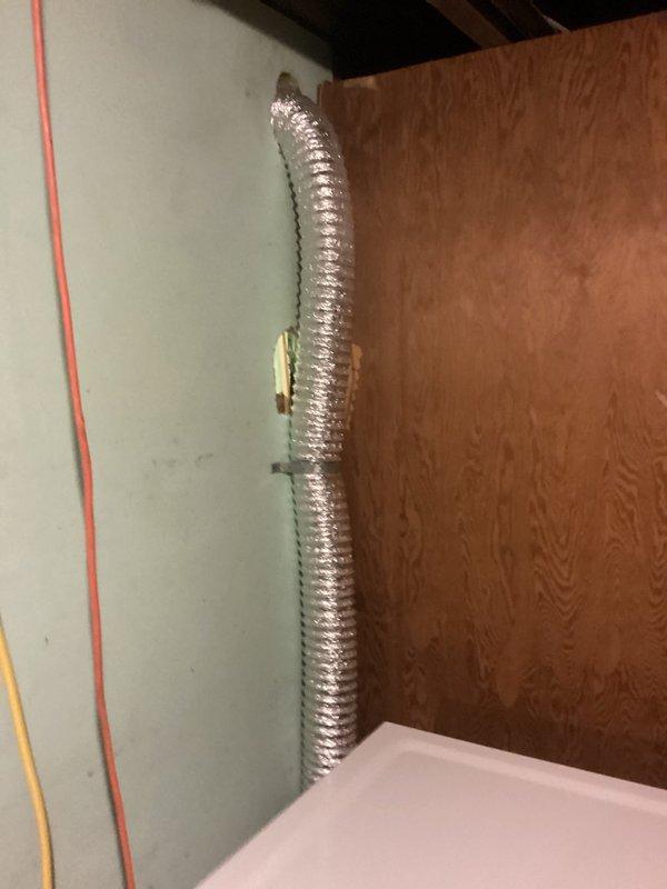 Installed a flexible aluminum dryer vent duct running along the wall below the ceiling and routed it through the exterior wall penetration, securing it with metal band clamps for proper support and alignment. Connected the duct to the dryer to provide exhaust ventilation, and confirmed a tight, unobstructed run with secure fittings.